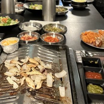 Moohan Korean BBQ - Table set with side dishes, sauces, and onions on the grill. - Korean Near Me - Los Angeles, California