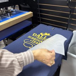 DTF Dallas - Heat press applying a DTF transfer onto apparel during custom t-shirt production at DTF Dallas in Richardson, Texas.