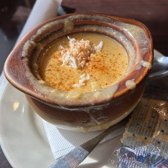Oscar's Alehouse - Cream of Crab soup (rather small bowl though) - A bowl of Cream of Crab soup with a sprinkle of spices, served in a rustic ceramic bowl on a white plate with a spoon. - New American Near Me - Eldersburg, Maryland
