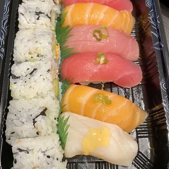 Hanami Express - Sushi lunch - The image shows a black plastic sushi bento box with a variety of sushi items. On the left side, there are rice rolls with sesame seeds and seaweed. On the right side, there are slices of sashimi, including tuna, salmon, and white fish, garnished with green onion and a small amount of wasabi. The sashimi is arranged in a neat row, with some garnishes placed on top. The presentation is clean and organized, suitable for takeaway or quick service. - Japanese Near Me - Austintown, Ohio