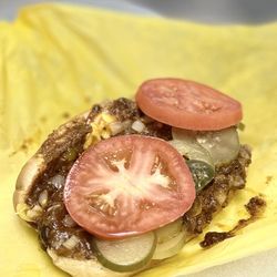 Original Tommy's - Chili Cheese Dog: Hot dog on a bun w/chili, cheese, mustard, onions, extra pickles & tomato + grilled onions/yellow peppers | $8.05