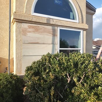Window World of Albuquerque - Front outside - The image shows the front exterior of a house with a large window, a bush in the foreground, and a ladder on the right side, indicating ongoing construction or renovation. - Windows Installation Near Me - Albuquerque, New Mexico