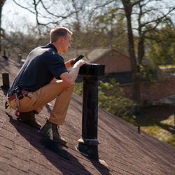 Rock Solid Inspections - Home inspector taking a picture of missing screens on gas roof vent during a roof inspection.