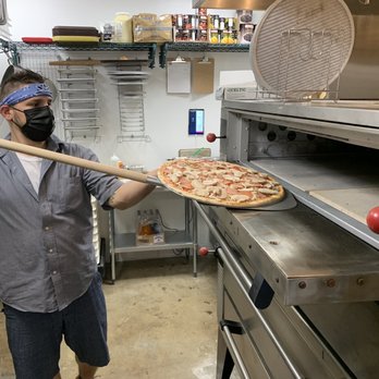 The Pizza Pitt - a man wearing a face mask and holding a pizza in front of an oven - Pizza Near Me - Atlanta, Georgia The Pizza Pitt - a man wearing a face mask and holding a pizza in front of an oven - Pizza Near Me - Atlanta, Georgia