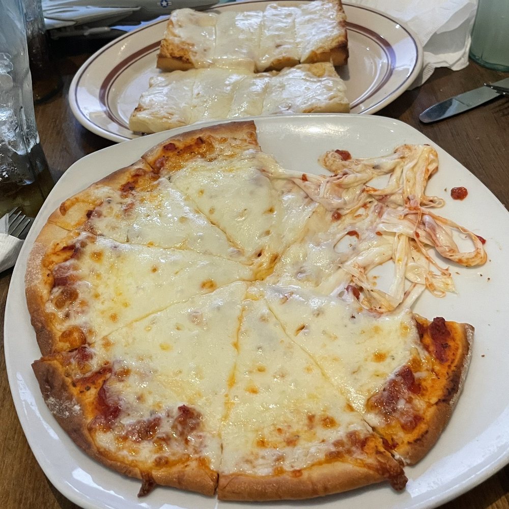 Lombardi's - Cheese pizza (with cheesy garlic bread in the background) - Italian Near Me - Cambria, California Lombardi's - Cheese pizza (with cheesy garlic bread in the background) - Italian Near Me - Cambria, California