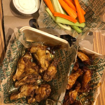 Wingstop - Spicy Korean & Lemon Pepper - Chicken wings with two different sauces are served with celery and carrot sticks and a dipping sauce in a restaurant setting. - Chicken Wings Near Me - Overland, Missouri
