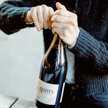 Living Roots Rochester - a person holding a bottle of wine - Wineries Near Me - Rochester, New York Living Roots Rochester - a person holding a bottle of wine - Wineries Near Me - Rochester, New York