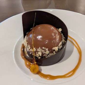 American Harvest - Hazelnut and chocolate mousse dessert, encircled by a chocolate ring and gooey caramel. - Brewpubs Near Me - Livonia, Michigan American Harvest - Hazelnut and chocolate mousse dessert, encircled by a chocolate ring and gooey caramel. - Brewpubs Near Me - Livonia, Michigan