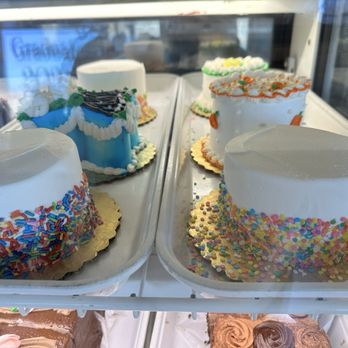 Mazzetti's Bakery - Assorted decorated cakes with colorful sprinkles and icing are shown in a bakery display case, with some cakes featuring white icing and others with detailed piping. - Bakeries Near Me - Pacifica, California