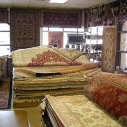 Inside the store. Stacks of rugs to go through, great designs, high quality, all different sizes and colors.