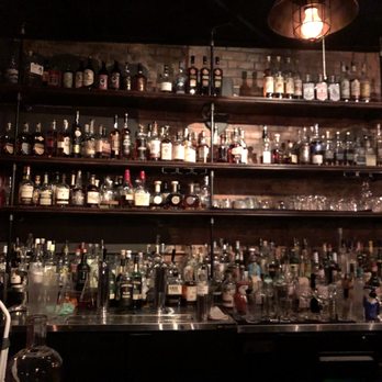 District Elleven - shelves of liquor bottles on a brick wall - Cocktail Bars Near Me - Colorado Springs, Colorado