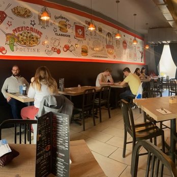 Poutineville - a woman sitting at a table in a restaurant - Poutineries Near Me - Montreal, Quebec