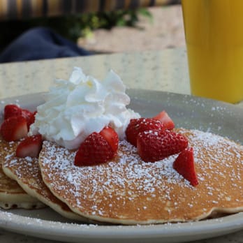 Breakfast Club - Pancakes with chocolate chips inside, strawberries and whipped cream on top. Pineapple juice in the corner. - Breakfast & Brunch Near Me - Phoenix, Arizona