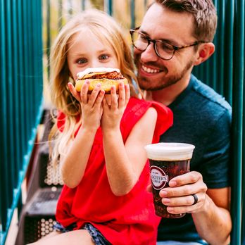 Scooter's Coffee - a father and daughter eating a hot dog - Coffee & Tea Near Me - Marriott-Slaterville, Utah