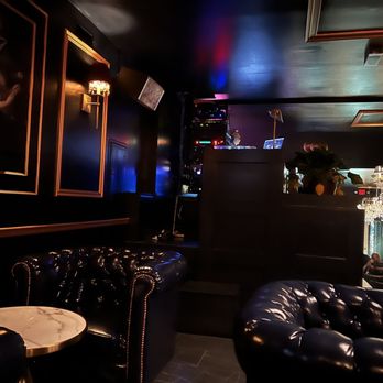 Destino Lab - a dark room with a chandelier and leather chairs - Lounges Near Me - Elizabeth, New Jersey