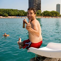 Chicago TikiBoat - Jumping into fun with Chicago Tiki Boat! A guest gives a thumbs up and cheers with a beer before taking a plunge off our boat's slide.