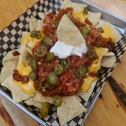 Brisket Nachos Tortilla chips topped with smoked beef brisket chili, melted cheese, salsa, jalapeño, and sour cream.
