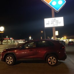 a car parked in front of a domino sign a car parked in front of a domino sign
