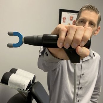 Foundation Chiropractic - Dr. Brandt Adams holding a Mechanical Motion Adjuster - Chiropractors Near Me - Hampton, Georgia