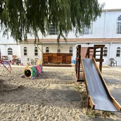 Southern California Montessori School Inc - The playground. The small slide, sandbox (in the background) and the crawling caterpillar.