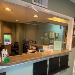 McKenna Dental - Reception desk in a dental office with a glass wall, featuring a welcoming atmosphere for patients.