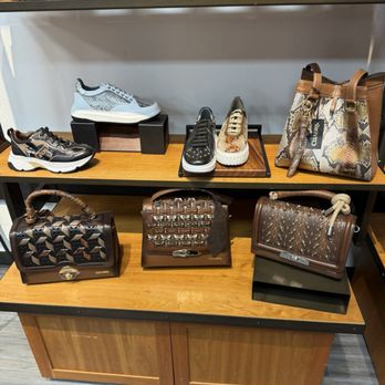Cuadra - Showcase of designer footwear and handbags, including sneakers, boots, and purses, arranged on shelves and a wooden table. - Shoe Stores Near Me - Austin, Texas