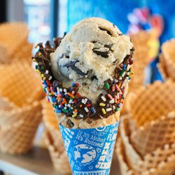 Ben & Jerry’s - A Ben & Jerry's freshly baked dipped waffle cone with sprinkles in front of waffle cone display.