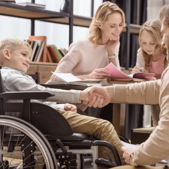 Coughlin Cares - a man in a wheelchair shaking hands with a woman and two children - Handyman Near Me - Saint Clair, Michigan