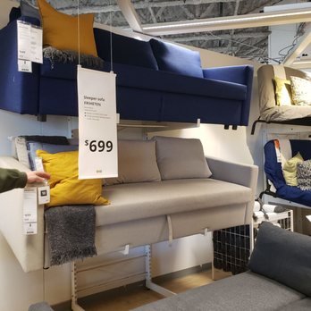 IKEA - In store display is nice, but out of stock in store and online. - A beige sleeper sofa with yellow and gray pillows is displayed on a store wall, with a price tag of $699, surrounded by other sofas and furniture. - Home Decor Near Me - Schaumburg, Illinois
