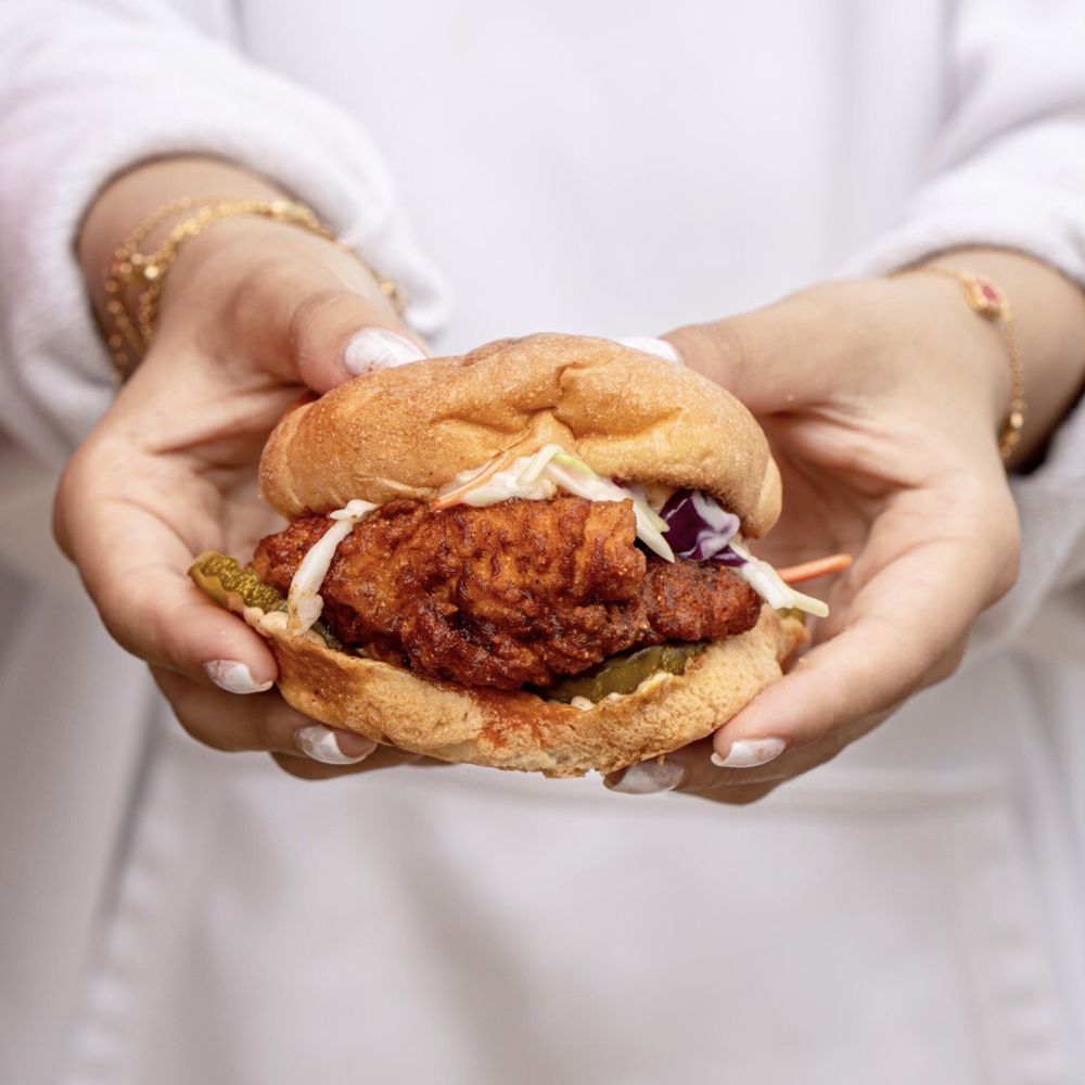 Holy Cluck - a woman holding a chicken sandwich - Sandwiches Near Me - Dearborn, Michigan