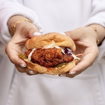 Holy Cluck - a woman holding a chicken sandwich - Sandwiches Near Me - Dearborn, Michigan Holy Cluck - a woman holding a chicken sandwich - Sandwiches Near Me - Dearborn, Michigan