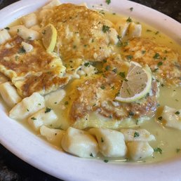 Gnocchi - A dish featuring chicken Francese topped with sauce, served with homemade gnocchi and garnished with lemon slices and parsley.