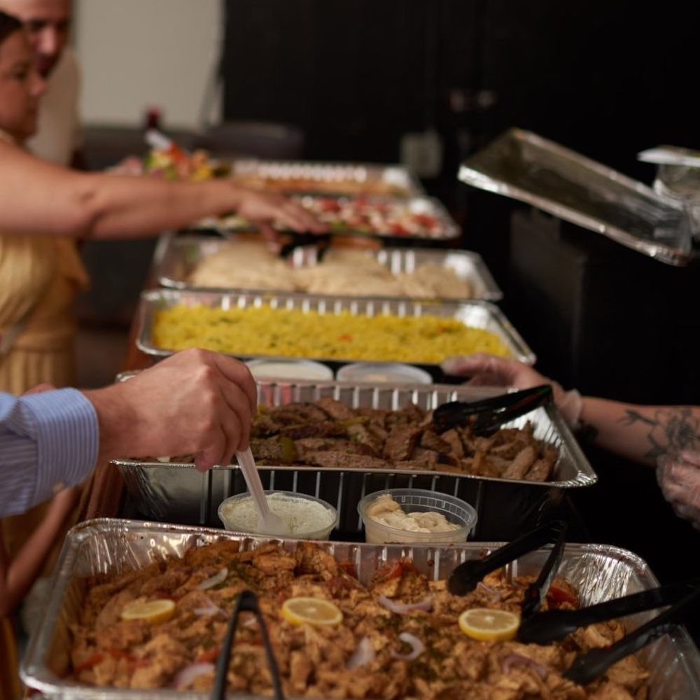 a group of people serving themselves at a buffet a group of people serving themselves at a buffet