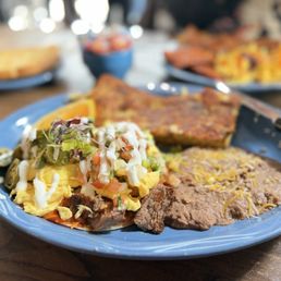 Huevos rancheros, mole tortilla with scramble eggs, sour cream, guacamole, and tomato, fried beans with herb potatoes