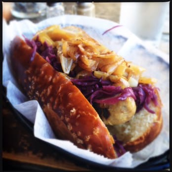 Max Bratwurst und Bier - Beer and cheese brat on a pretzel bun topped with red cabbage and carmelized onions. - German Near Me - Astoria, New York Max Bratwurst und Bier - Beer and cheese brat on a pretzel bun topped with red cabbage and carmelized onions. - German Near Me - Astoria, New York