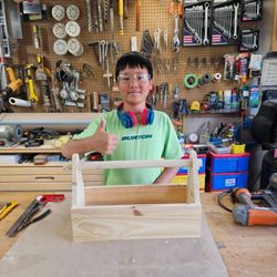 GTA WoodWorks - Smiling boy giving a thumbs up while showcasing a wooden toolbox he built in a Toronto woodworking class.