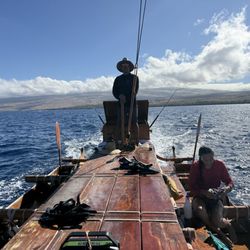 Authentic Hawaiian Sails - Captain Koco at the helm and a family crew member readying snorkel gear.