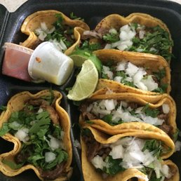 a tray of tacos with salsa and lime wedges