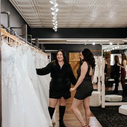 Astraea Bridal - Leslee showing a Bride a couple gowns