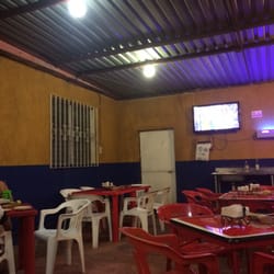 La Victoria - El interior del local, con mesas de plástico, techo y televisor.