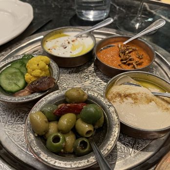 Dalida - The assortment of hummus, pickled vegetables, and olives, that accompany the broken bread. - Mediterranean Near Me - San Francisco, California