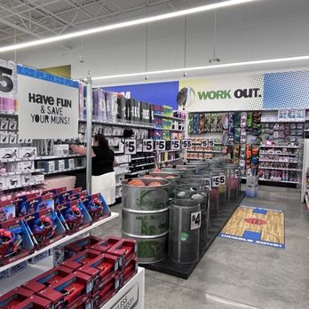 Five Below - Sports - A store aisle displays sports balls, toys, and accessories, with signs indicating prices and promotional messages. - Accessories Near Me - Morgan Hill, California