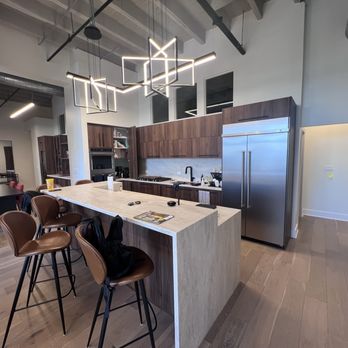 AR Remodeling Group - A modern kitchen features wooden cabinetry, a large island with seating, stainless steel appliances, and geometric pendant lighting. - General Contractors Near Me - Chicago , Illinois