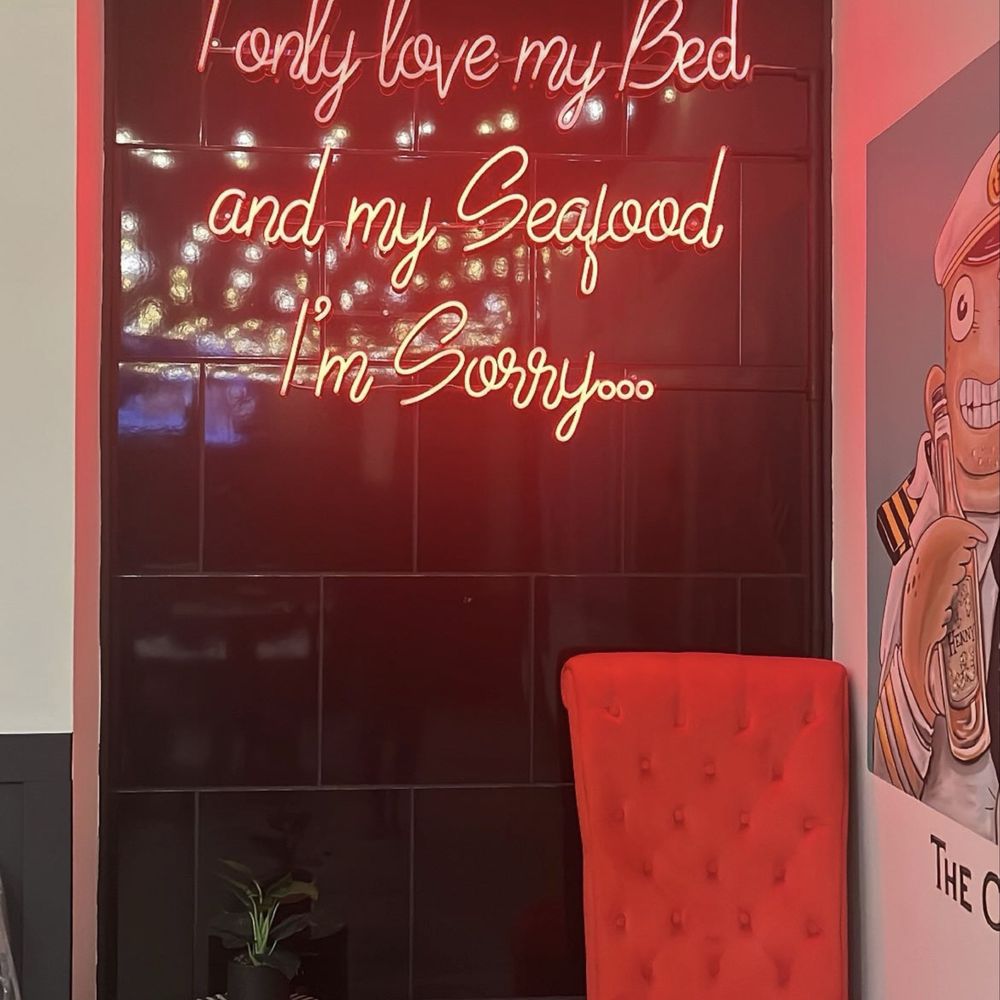 Cap't Loui - a red chair and a neon sign - Cajun/Creole Near Me - Providence, Rhode Island