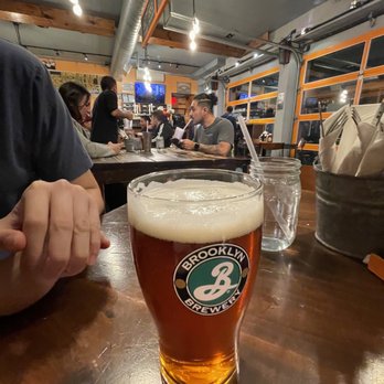 Burger Club - a glass of beer on a table - Burgers Near Me - Astoria, New York Burger Club - a glass of beer on a table - Burgers Near Me - Astoria, New York