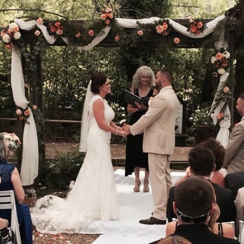 Monte Verde Inn - Out wedding couple under the canopy of huge trees and the beautifully decorated arbor - Venues & Event Spaces Near Me - Foresthill, California