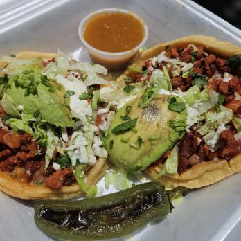 El Queretano - Sopes de Al Pastor - Two tacos filled with seasoned meat, lettuce, and avocado slices, served with a small cup of sauce and a roasted jalapeño pepper. - Food Trucks Near Me - Santa Fe, New Mexico