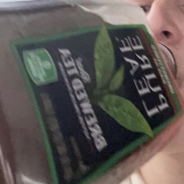 The iced tea I love. - A person is holding and drinking from a Lipton iced tea bottle, with part of their face visible in the background.