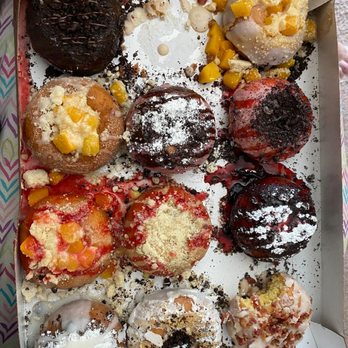 Duck Donuts - Best Birthday Treat - A box contains twelve donuts with different toppings, including chocolate, fruit glazes, and sprinkles, arranged in a grid. - Donuts Near Me - Lancaster, Pennsylvania