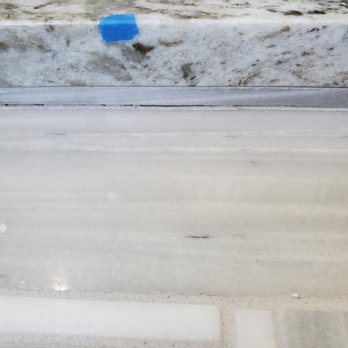 Centex Bath - Grout missing on shower floor - The image shows a tiled surface with visible missing grout and a small piece of blue painter's tape attached to the tile. - General Contractors Near Me - Round Rock, Texas
